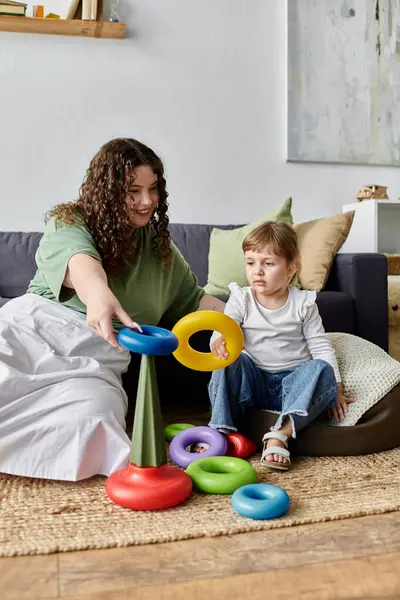 A beautiful plus size woman engages her daughter in a playful activity with colorful rings. — Stock Photo