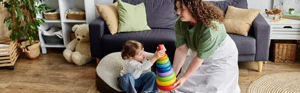 A loving plus size woman plays with her daughter, stacking colorful rings on a cozy day at home. — Stock Photo