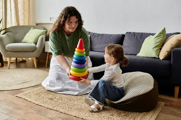 A mother and daughter share laughter while stacking colorful rings on a cozy afternoon. — Stock Photo