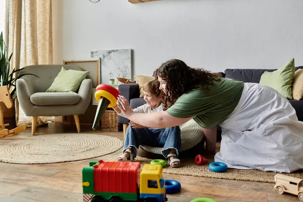 Eine Plus-Size-Mutter engagiert sich liebevoll für ihre kleine Tochter, umgeben von spielerischem Spielzeug zu Hause. — Stockfoto