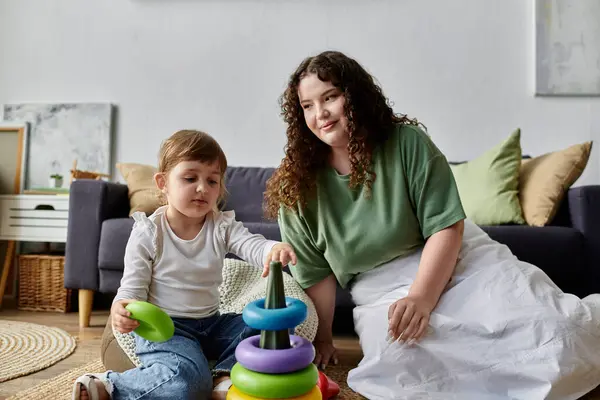 Una madre e sua figlia godono di un momento giocoso insieme, impilando anelli colorati su un tappeto accogliente. — Foto stock