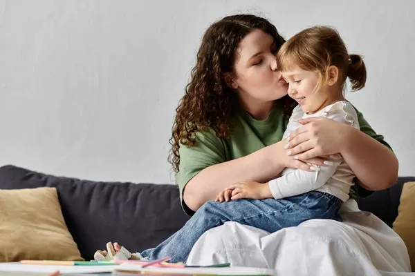 A mother lovingly kisses her daughter as they share a moment of creativity at home together. — Stock Photo