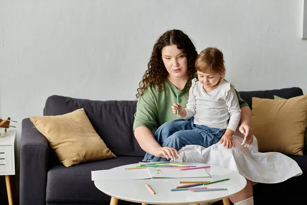 Una madre y su hija participan en una colorida actividad de dibujo juntas en un sofá suave. - foto de stock