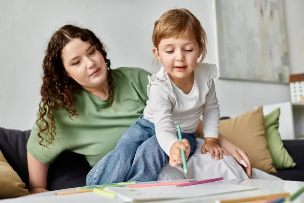 A mother watches her daughter joyfully draw and express her creativity at home. — Stock Photo