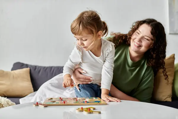 A loving mother enjoys playful moments with her daughter while they engage in an activity together. — Stock Photo