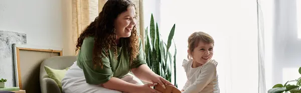 A beautiful plus size woman and her daughter share laughter and joy while playing together indoors. — Stock Photo