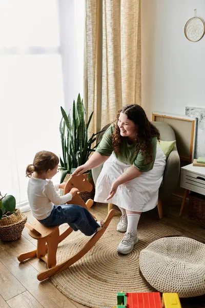 A delighted mother interacts playfully with her young daughter in their cheerful home space. — Stock Photo