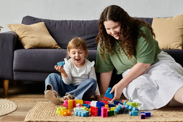 A loving plus size mother and her daughter enjoy quality time while building with colorful blocks. — Stock Photo