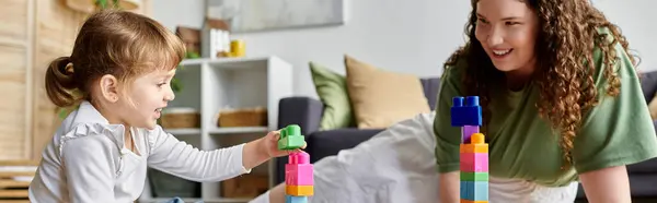 A plus size woman and her daughter delight in stacking colorful blocks together on the floor. — Stock Photo