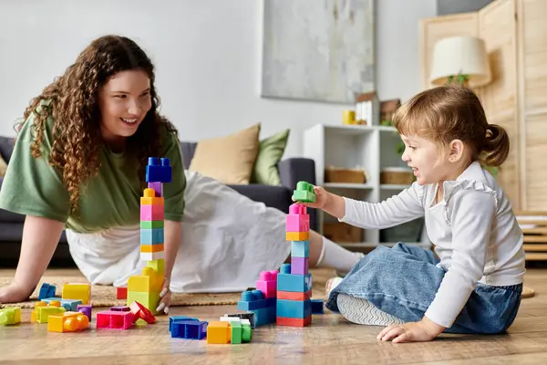 A plus size woman and her daughter playfully create with colorful building blocks. — Stock Photo
