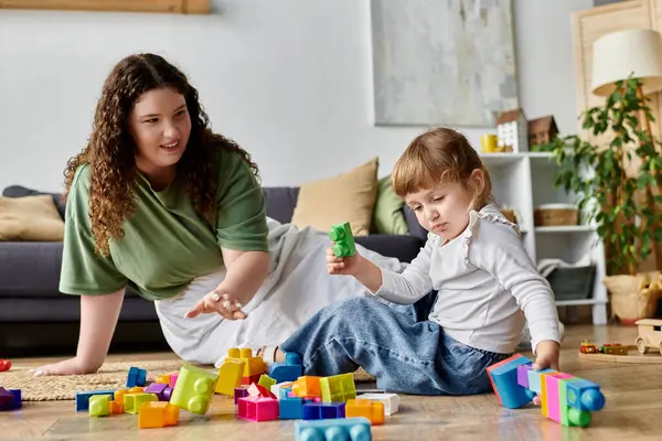 Una madre y su hija disfrutan de un tiempo de calidad jugando con vibrantes bloques de construcción en el suelo. - foto de stock