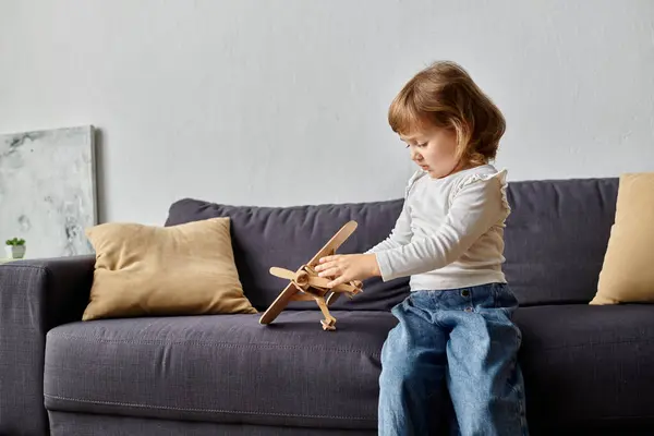 Adorable girl in casual attire playing with her toy plane at home. — Stock Photo