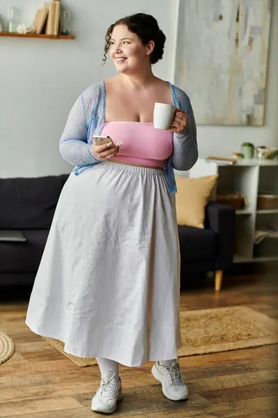 A woman enjoys a warm drink while interacting with her phone. — Stock Photo