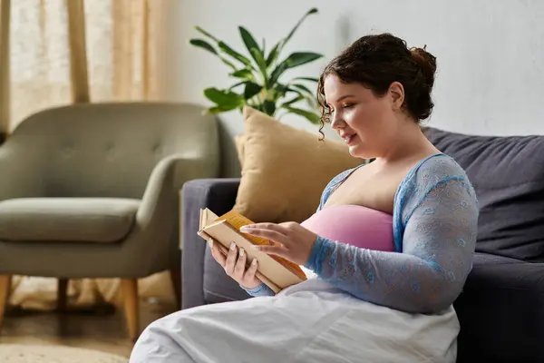 Delighted plus size woman in cozy homewear holding  book. — Stock Photo