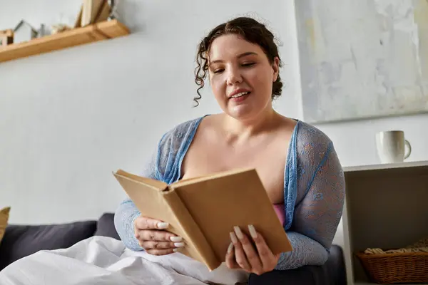 Positive young woman in cozy homewear holding book in hands, at home. — Stock Photo