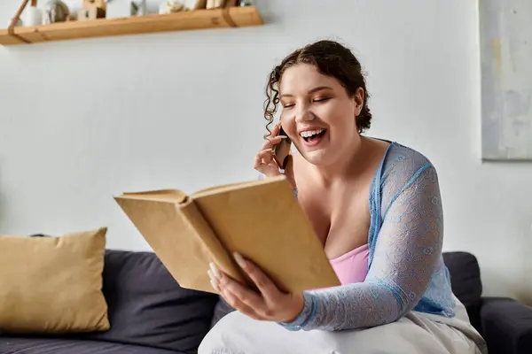 Joyous young woman in cozy homewear holding book in hands, at home. — Stock Photo