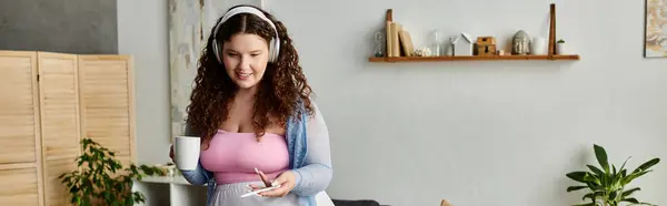 Jolly woman with curly hair and comfy vibrant attire at home. — Stock Photo