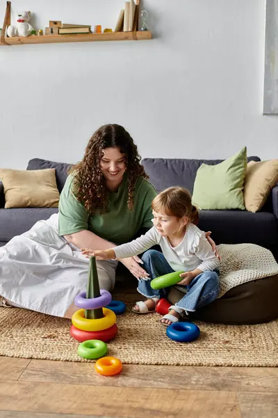 A nurturing plus size woman interacts playfully with her daughter on the cozy floor. — Stock Photo
