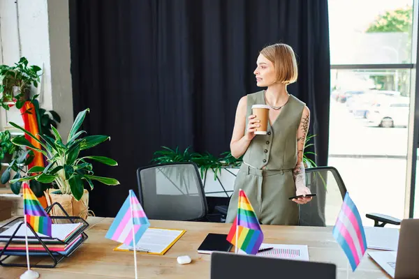 Una donna sta con fiducia tenendo un caffè, abbracciando la diversità sul posto di lavoro con orgoglio. — Foto stock