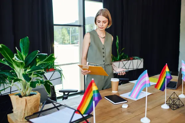 A confident worker engages with documents while surrounded by colorful pride flags and plants. — Stock Photo