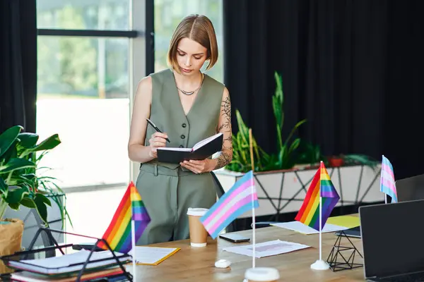 Woman member in a stylish outfit notes ideas at a workspace adorned with pride flags. — Stock Photo