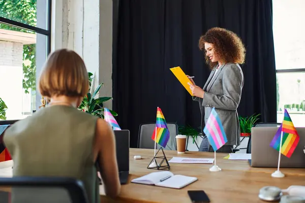 I colleghi LGBTQ stimolano la creatività in una vivace discussione nel loro luminoso ufficio. — Foto stock