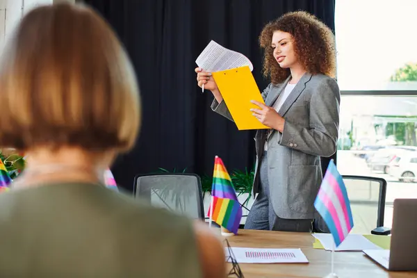 A woman passionately presents LGBTQ initiatives to her engaged coworkers in the office. — Stock Photo