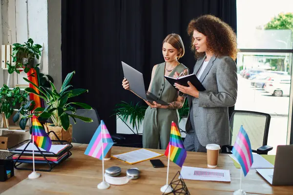 Two colleagues engage in a creative discussion while surrounded by symbols of the LGBTQ community. — Stock Photo