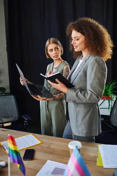 Two coworkers discuss important documents while showcasing pride in their workplace culture. — Stock Photo
