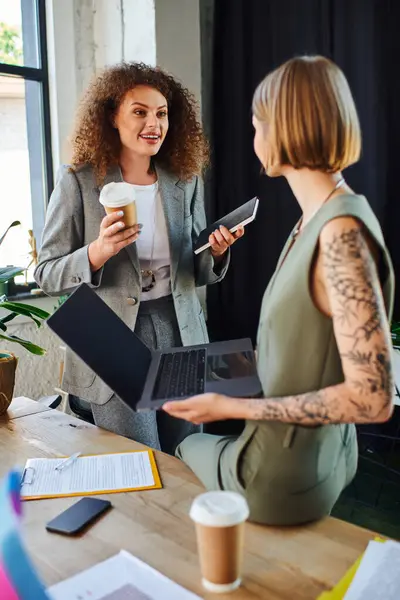 Two colleagues enjoy a lively conversation while holding drinks in a modern workspace. — Stock Photo