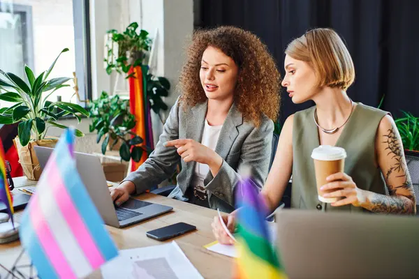 Colleagues share ideas over laptops while celebrating diversity in their workspace. — Stock Photo