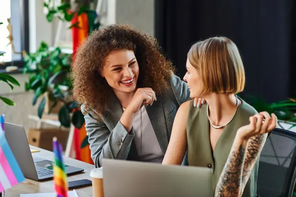 Two coworkers enjoy a light moment, embracing their identities in a welcoming workspace. — Stock Photo