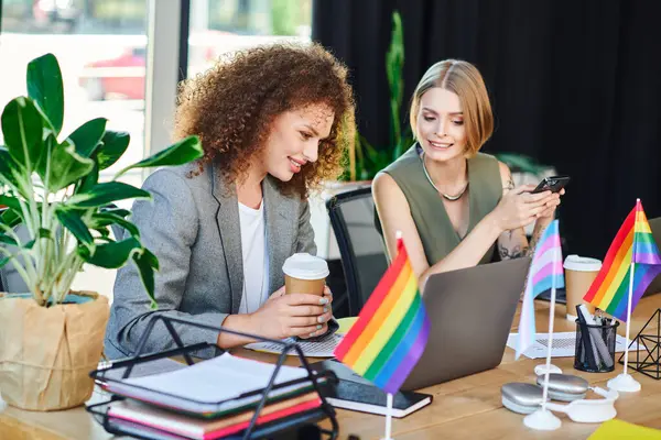 Two coworkers discuss lively amid LGBT symbols and greenery. — Stock Photo