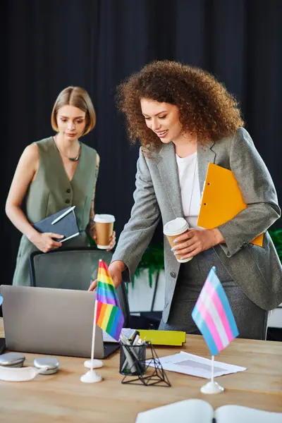 Dos entusiastas compañeros de trabajo intercambian ideas mientras apoyan a la comunidad LGBTQ en su espacio de trabajo. - foto de stock
