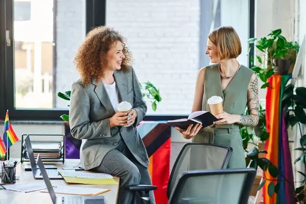 Two colleagues share a joyful moment over coffee, discussing ideas in an inclusive workspace. — Stock Photo