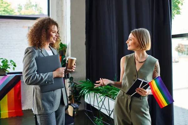 Two coworkers engage in a lively conversation, showcasing pride in their workplace. — Stock Photo