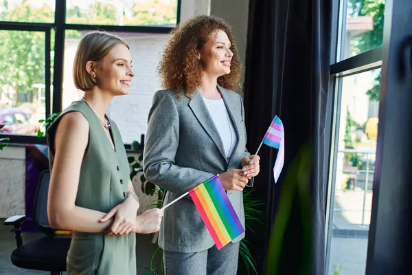 Coworkers bond and celebrate their pride, holding flags while enjoying sunny office views. — Stock Photo