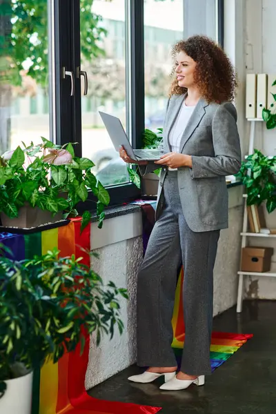 A professional engages with colleagues while promoting LGBTQ pride in a sunny office setting. — Stock Photo