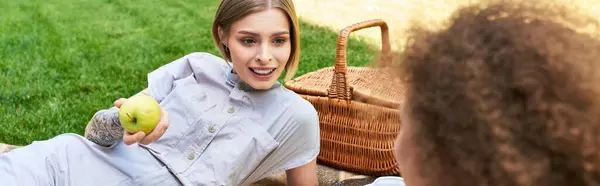 Zwei Freunde teilen Lachen und Snacks, während sie es sich auf einer Decke im Park gemütlich machen. — Stockfoto