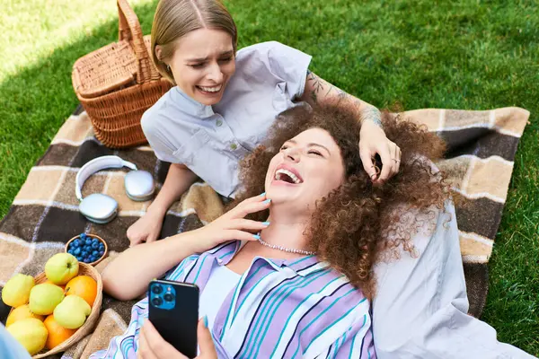 Two friends share joyful laughs and good times while lounging on a picnic blanket outdoors. — Stock Photo