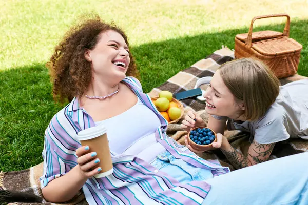 Due giovani donne si godono un momento giocoso all'aria aperta, circondate da frutta e risate. — Foto stock