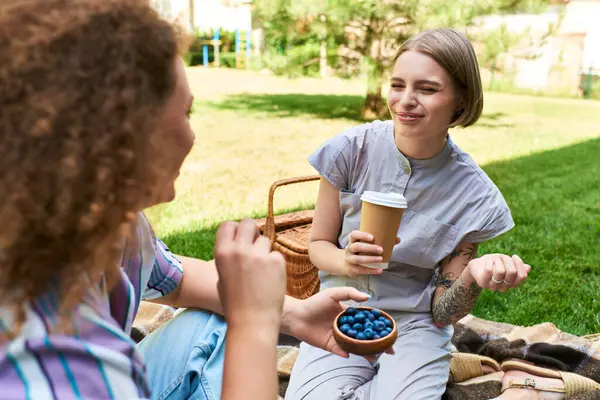 Two friends enjoy a lovely outdoor picnic, laughing and savoring fresh blueberries together. — Stock Photo