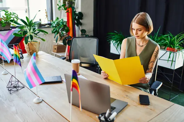 A focused individual reviews documents amidst an inclusive environment filled with pride flags. — Stock Photo