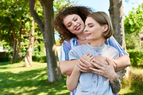 Dos mujeres jóvenes aprecian un momento alegre al aire libre, abrazando la amistad bajo el cálido sol. - foto de stock