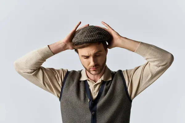 A handsome man carefully places his cap, highlighting his dapper style and thoughtful demeanor. — Stock Photo