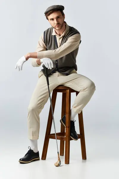 A fashionable man in a dapper outfit showcases his style while seated on a stool. — Stock Photo