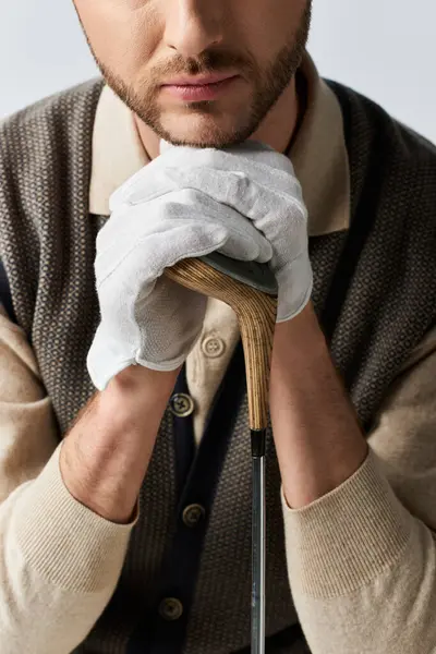 Ein gutaussehender Mann in stylischen Handschuhen posiert mit einem Golfschläger, sprüht vor Charme und Selbstbewusstsein. — Stockfoto