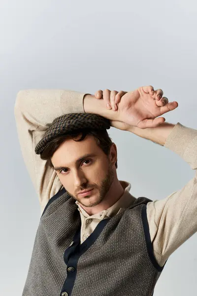 Un joven refinado vestido con atuendo clásico alcanza una pose segura, mostrando elegancia. - foto de stock