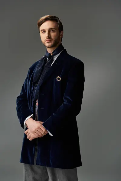 Ein gutaussehender Dandy steht selbstbewusst da und präsentiert seine modische Kleidung vor einem weichen Hintergrund. — Stockfoto