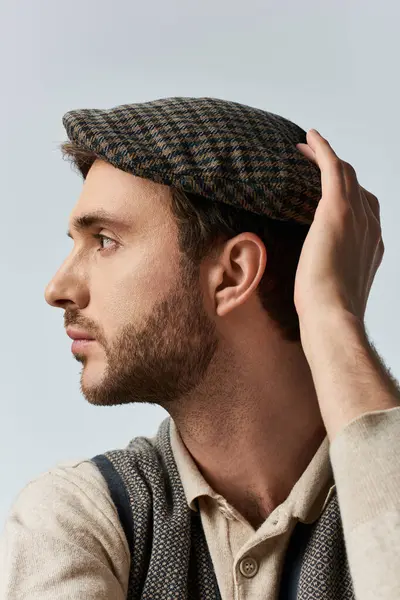 A fashionable man in vintage attire showcases his elegant style while adjusting his cap. — Stock Photo